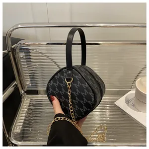 Close-up of mini round bag with grey M pattern and gold chain strap detail