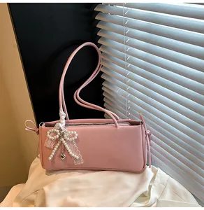 Detail of pink shoulder bag with lace bow, pearl strings and heart pendant