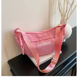 Detailed view of pink nylon dumpling bag with FASHION letter print and braided zipper pull