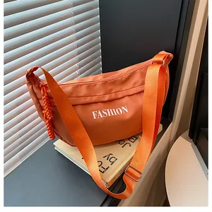 Detail of orange nylon dumpling bag with FASHION lettering and adjustable wide strap