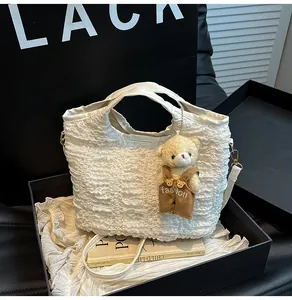 Detail of white pleated bucket bag with cute bear charm inside a black gift box