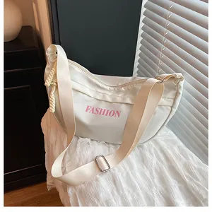 Close-up of a white nylon half-moon bag with pink fashion lettering and wide strap