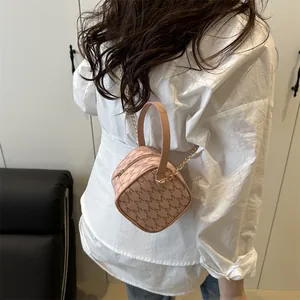 Pink mini round crossbody bag with repeating letter pattern and golden chain strap