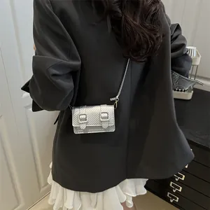 Elegant metallic silver square crossbody bag with textured finish on a female model