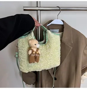 Detail of light green pleated bucket bag with a cute plush bear charm on the side
