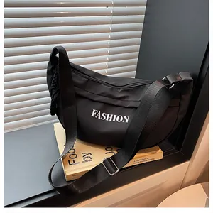 Detail of black crescent crossbody bag with white FASHION lettering and nylon strap