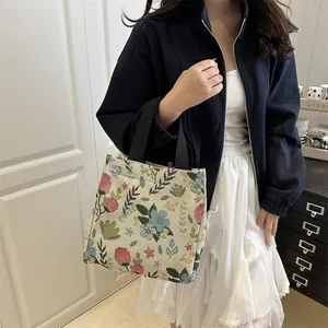 Floral tapestry tote bag with black handles and vibrant embroidered flower patterns