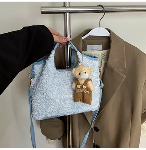 Detail of light blue pleated bucket bag with a cute bear charm and golden hardware detail