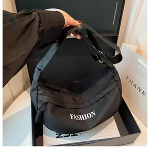 Detail of black nylon hobo bag with FASHION lettering and adjustable fabric strap
