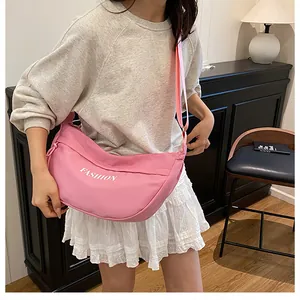 Detail of pink canvas dumpling bag showing FASHION print and adjustable strap
