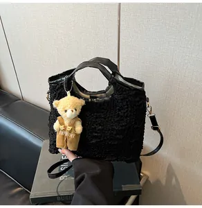 Detail of black wavy textured bucket bag with fluffy bear charm and leather handles