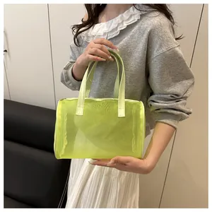 Detail view of fluorescent green mesh handbag featuring leather handles and zipper closure