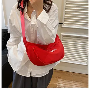 Detail view of red nylon crescent bag featuring white FASHION print and adjustable strap