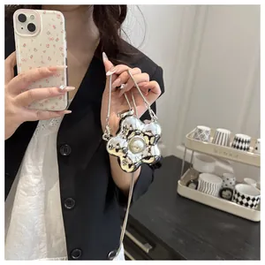 Detail of a mini silver flower crossbody bag with pearl center and snake chain strap