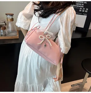 Close-up of pink underarm bag featuring pearl bow decoration and delicate lace details