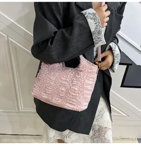 Detail of light pink pleated bucket bag with ruffled texture and golden hardware accents