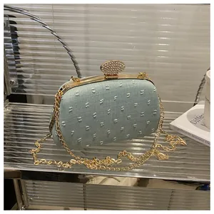 Detail of mint green textured evening clutch with sparkling rhinestone clasp and gold chain