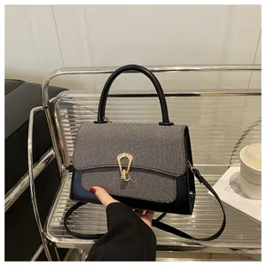 Close-up of black leather and grey twill crossbody bag with golden horseshoe buckle