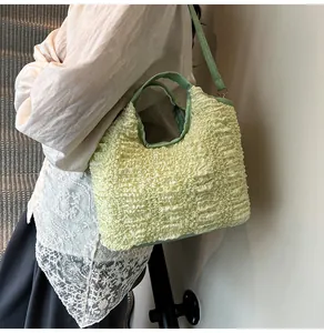 Detailed view of light green pleated bucket bag with textured leather handle for women