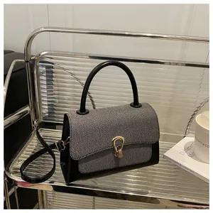 Detail of elegant two-tone crossbody bag featuring tweed flap and gold U-shaped metal lock