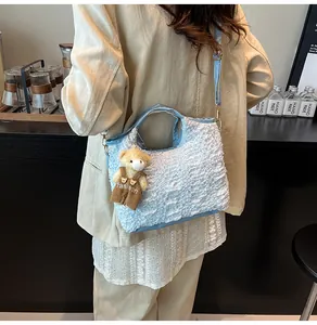 Detail of light blue bubble textured crossbody bag with a cute teddy bear charm
