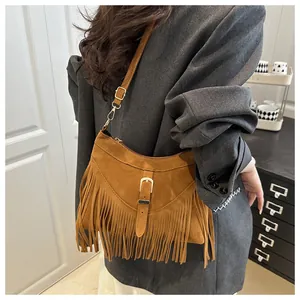 Detail of tan suede tote bag featuring long fringes and vintage metal buckle strap