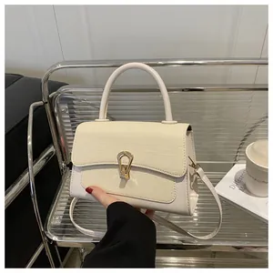 Detail of cream leather handbag featuring woven texture flap and golden horseshoe buckle