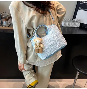 Detail of light blue pleated bucket bag featuring bubble texture and a cute bear charm