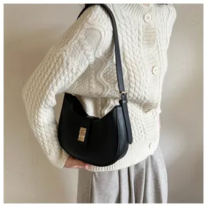 Detail of a black half-moon hobo bag with a gold buckle clasp and matte leather texture