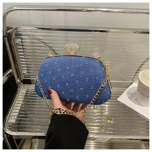 Detail of blue denim clutch bag featuring gold chain and sparkling rhinestone clasp