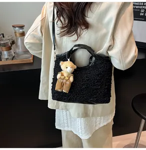 Detail of black pleated bucket bag with plush bear charm and faux leather handle