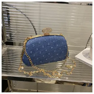 Detailed macro of dark blue denim evening clutch with gold metal frame and chain strap
