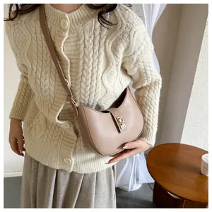 Detail of hobo crossbody bag in beige leather with metal buckle on knit cardigan