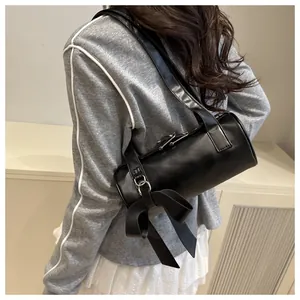 Close-up of black cylinder shoulder bag with a large bow detail and sleek PU leather finish
