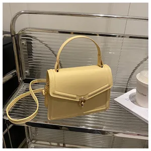 Détail d'un sac à main en cuir jaune clair avec fermoir rotatif en métal doré élégant