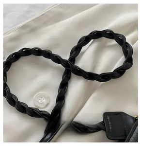 Detail of a black braided leather strap on a shoulder bag with elegant texture