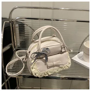 Detail of cream white bag with lace trim, bows, and detachable strap on display