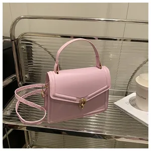Détail du sac à bandoulière rose clair avec fermoir rotatif doré et texture en cuir lisse