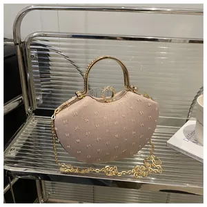 Close-up of beige rhinestone handbag with gold metal handle and textured fabric detail