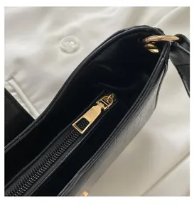 Detail of a smooth gold metal zipper on a black crocodile textured handbag