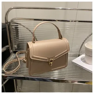 Détail d'un sac à main beige en similicuir avec fermoir rotatif doré et texture lisse