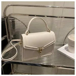 Détail d'un sac bandoulière beige avec fermoir doré posé sur une étagère design