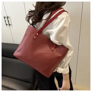 Detail of red woven tote bag featuring textured faux leather and long shoulder straps