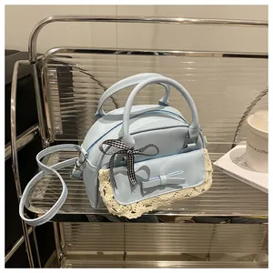 Detail of light blue leather lace handbag with bow accents and checkered scarf on handle