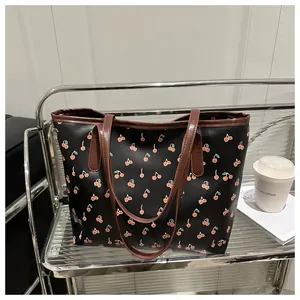 Vue détaillée du sac cabas noir imprimé cerise sur un support métallique design