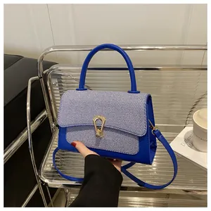 Detail view of royal blue handbag with striped flap and golden buckle on elegant display