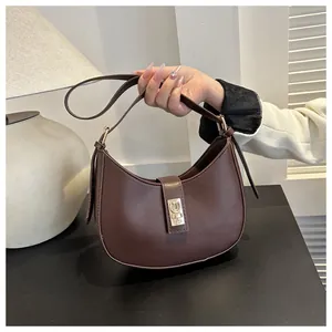 Detail shot of a brown leather crescent shoulder bag with elegant gold buckle hardware
