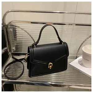 Détail d'un sac à main en cuir noir avec serrure dorée sur une étagère argentée moderne