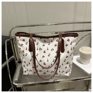 Gros plan d'un sac cabas blanc à imprimé cerise avec des anses en similicuir marron poli