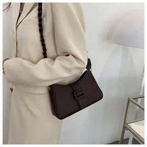 Close-up of dark brown crocodile embossed shoulder bag with unique braided rope strap design
